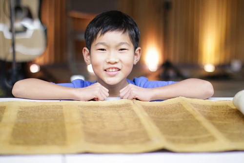 Boy in front of a Biblical scroll